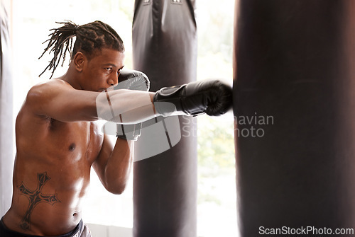 Image of Muscle, punching bag and black man in gym for exercise, boxing challenge or competition training. Power, fitness and serious champion boxer at workout with confidence, fight and energy in sports club