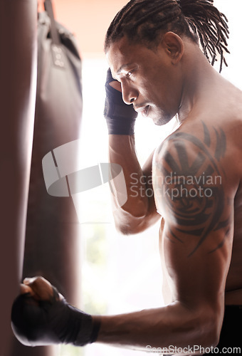 Image of Exercise, body and punch with black man kickboxing in gym for health, power or combat sports training. Fitness, mma or martial arts and young shirtless fighter with punching bag for strength workout