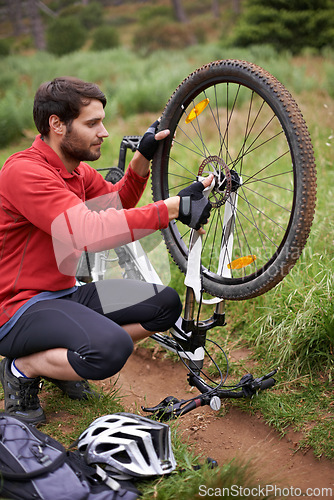 Image of Exercise, bicycle and fixing wheel with man cyclist in countryside for sports, hobby or cardio training. Fitness, cycling or tyre puncture with young athlete and bike outdoor in nature for workout