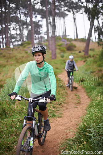 Image of Woman, bike and cycling outdoor on trail for exercise, workout or adventure in forest with fitness. People, cyclists and bicycle with helmet in woods or off road for sport, hobby and travel in nature