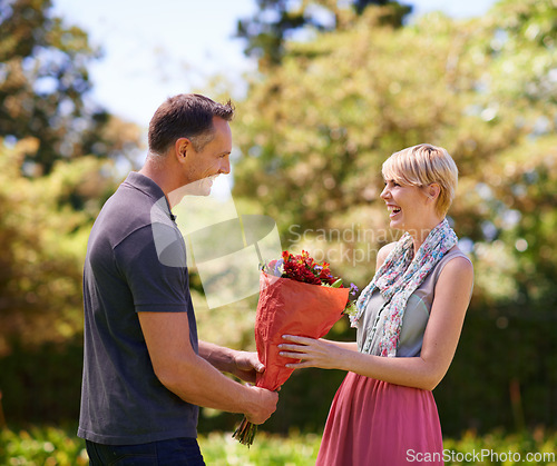 Image of Smile, couple and present of flowers in nature outdoor, bonding and date on valentines day. Bouquet, man and woman with gift for love, care and romantic connection of people laughing at park together