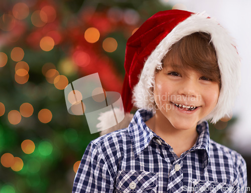 Image of Christmas, portrait and happy child in home with bokeh for festive celebration, party and holiday. Face, smile and boy in hat for xmas, laughing or excited facial expression in house in Australia