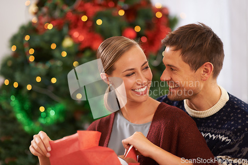 Image of Love, Christmas gift and couple in living room at home for festive celebration together. Smile, happy and young man and woman with holiday present box for xmas event or party at modern house.