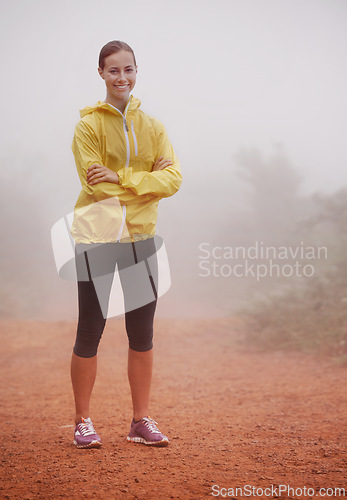 Image of Woman, portrait and arms crossed for fitness in forest with fog for exercise, morning routine and workout with smile. Athlete, face and person or happy on outdoor trail for wellness and healthy body