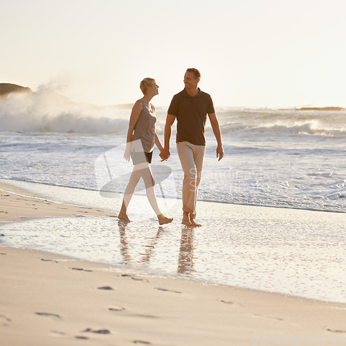 Image of Couple, walking and beach at sunset for romantic date, weekend getaway or honeymoon in Indonesia. Happy woman, man or people in love with smile for holding hands, bonding and rest and relaxation