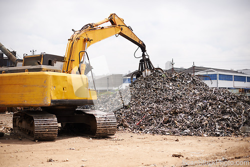 Image of Crane, machine and scrapyard to recycle metal for sustainability, manufacturing or stop pollution. Vehicle, tractor and outdoor in junkyard, plant or ecology for iron, steel industry and environment