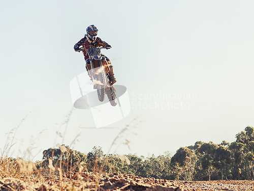 Image of Motorcycle, person and outdoor for jump in race on trail for competition, air and games on ground. Racer, motorbike and helmet for contest, motor cross and fast transport with flight in countryside