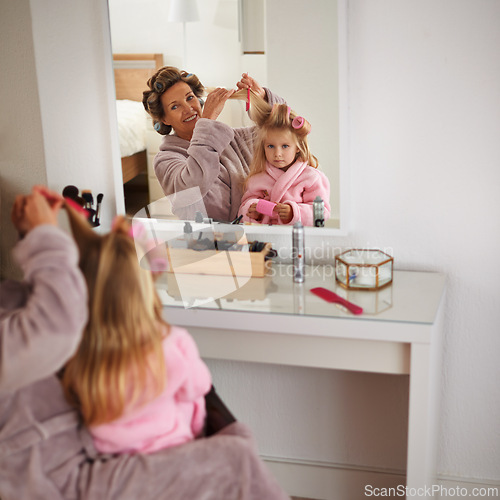 Image of Mom, daughter and playing with hair in mirror for beauty, care and helping or getting ready. Happy mother, family and girl or kid with rollers for hairstyle, fashion and bonding together at home
