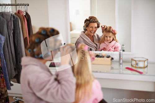 Image of Mother, child and playing with hair in mirror for beauty, care and helping or getting ready. Excited mom, family and daughter or kid with rollers for hairstyle, fashion and bonding together at home