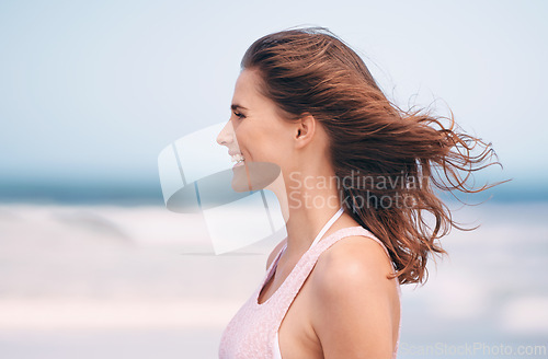 Image of Woman, wind and smile on beach environment for holiday destination or travel journey, happiness or blue sky. Female person, relax and seaside in Florida for outdoor paradise, fresh air or adventure