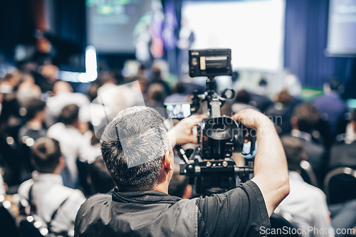 Image of Speaker giving a talk in conference hall at business event. Rear view of unrecognizable people in audience at the conference hall. Business and entrepreneurship concept.