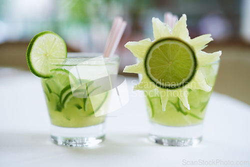 Image of Cocktail, alcohol and mojito with lime for drink on table for party, club and bar decoration. Glass, background and closeup of mocktail, beverage and liquid with fruit, ice and liquor in restaurant