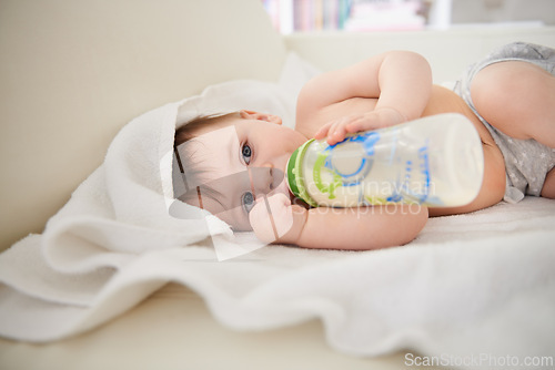 Image of Baby, bottle and relax with boy, calm and nutrition with wellness and childcare with blanket. Home, kid and newborn drinking milk with growth and development with peace and joyful with formula