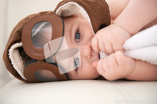 Image of Baby, portrait and pilot hat or happy at home on bed for childhood development for growth, blanket or comfortable. Kid, boy and face airplane flying accessory in apartment for peace, relaxing or rest