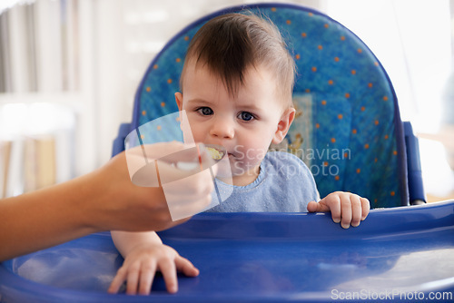 Image of Baby, hand and spoon for feeding food in chair for morning nutrition in apartment for eating meal, development or lunch. Kid, childcare and fingers for toddler dinner or wellness, hungry or vitamins