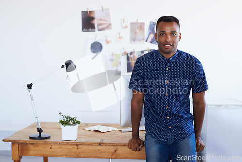 Image of Man, portrait and desk at creative studio or startup as .graphic designer with photographs, project planning or magazine. Male person, face and confidence or small business, entrepreneur or workspace