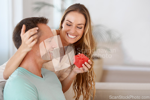 Image of Wife surprise or present for husband in home and giving on anniversary to celebrate marriage on couch. Woman, love and kindness with gift for man, romantic and bonding together on sofa with care