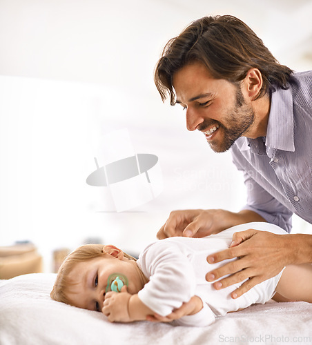 Image of Father, baby and happiness with play in home for healthy development, parenting and bonding in bedroom. Family, child and man with face, pacifier and comfort for relax, love and care on bed in house