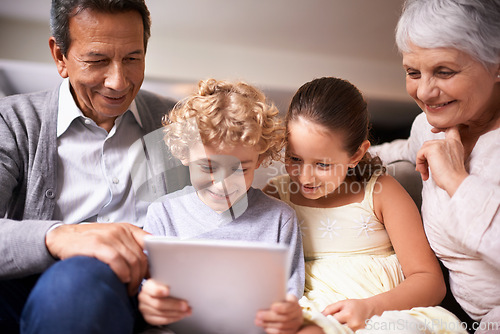 Image of Happy family, grandparents and kids with tablet on sofa for entertainment or social media at home. Grandma, grandpa and children with smile, hug and love on technology for bonding or game at house