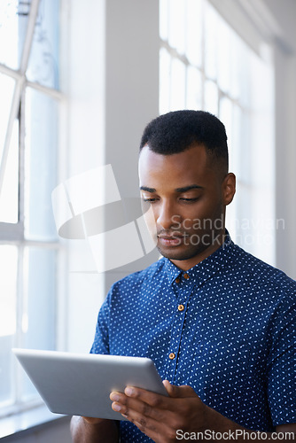 Image of Businessman, tablet and internet at window for communication, online search or networking in office. Entrepreneur, african employee and serious with technology for corporate email or planning at work