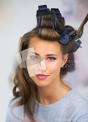 Image of Woman, face and smile with hair curlers for beauty, haircare and hairstyle with makeup or cosmetics at hairdresser. Person, happy and roller set for grooming, curling and getting ready with skincare