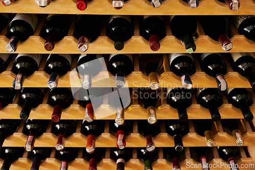 Image of Wine cellar, bottle and storage on rack in vineyard for restaurant stock, winery and shelf with alcohol display. Warehouse, drinks collection and beverage stack in basement with arrangement and row