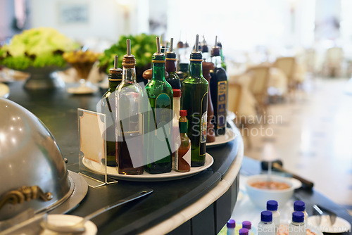 Image of Sauce, bottles and condiment in restaurant for food with hospitality industry for dining. Catering, cuisine and plate of flavors selection on counter for lunch, dinner or supper meal in cafeteria.