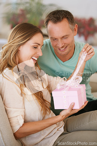 Image of Woman opening gift, man and happy with surprise for birthday or anniversary, love and support with romance. Couple in marriage, unboxing package with ribbon and present for token of appreciation