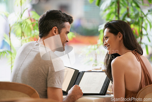 Image of Couple, restaurant and menu for conversation, selection and bonding on valentines day. People, love and romance at cafe or lunch choice for anniversary celebration, cuisine and happy at bistro