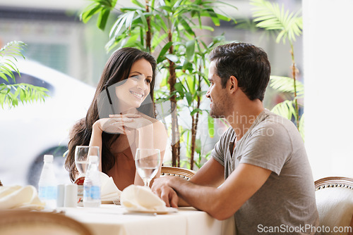 Image of Couple, restaurant and talking on date, love and bonding on valentines day. People, conversation and romance at cafe or smile for anniversary, together and alcohol at bistro on vacation or holiday