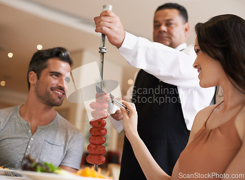 Image of Food, date and romance with couple in restaurant together for celebration or eating espetada. Love, meat or dinner with happy young man and woman in fine dining hospitality establishment for service