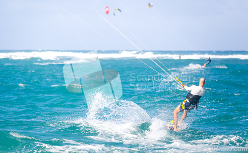 Image of Kiteboarding. Fun in the ocean. Extreme Sport Kitesurfing. Kitesurfer jumping high in the air performing triks during kitesurfing session.