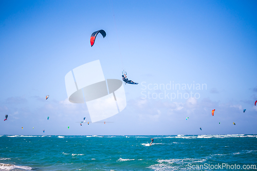 Image of Kiteboarding. Fun in the ocean. Extreme Sport Kitesurfing. Kitesurfer jumping high in the air performing triks during kitesurfing session.