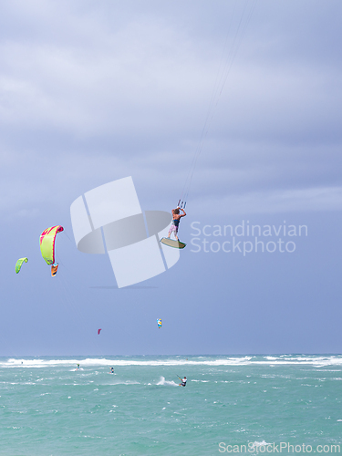 Image of Kiteboarding. Fun in the ocean. Extreme Sport Kitesurfing. Kitesurfer jumping high in the air performing triks during kitesurfing session.