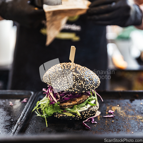 Image of Chef making healthy vegetarian salmon burgers outdoor on open kitchen, odprta kuhna, international food festival event. Street food ready to be served on a food stall.