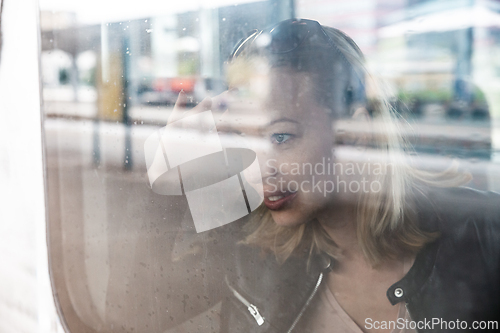 Image of Woman traveler contemplating outdoor view from window of train. Young lady on commute travel to work sitting in bus or train.