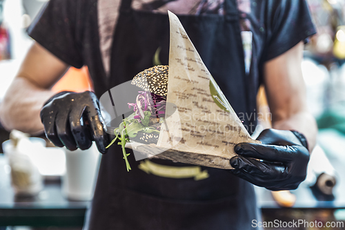 Image of Chef serving vegetarian salmon burgers outdoor on open kitchen, odprta kuhna, international food festival event. Street food being served on a food stall.