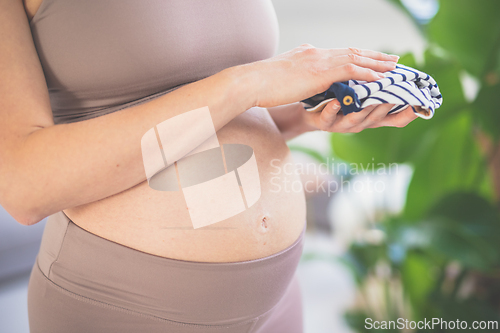 Image of Pregnant woman ready for delivery, holding little clothes for newborn baby. Pregnant woman belly. Pregnancy Concept. Pregnant tummy close up