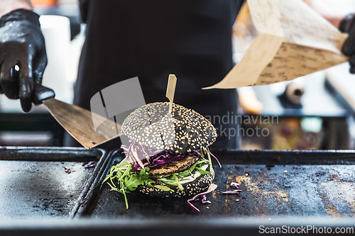 Image of Chef making healthy vegetarian salmon burgers outdoor on open kitchen, odprta kuhna, international food festival event. Street food ready to be served on a food stall.