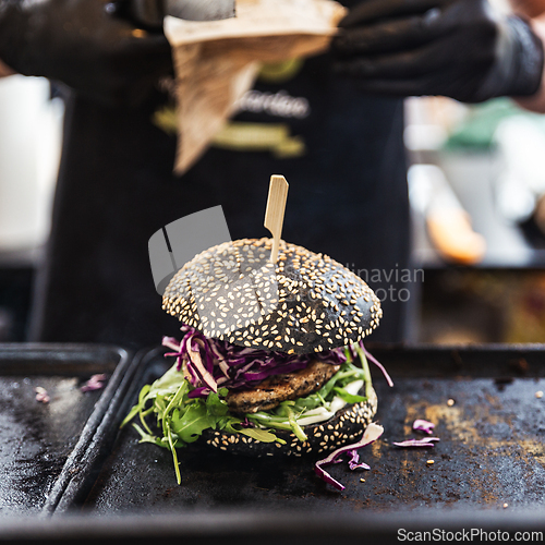 Image of Chef making healthy vegetarian salmon burgers outdoor on open kitchen, odprta kuhna, international food festival event. Street food ready to be served on a food stall.