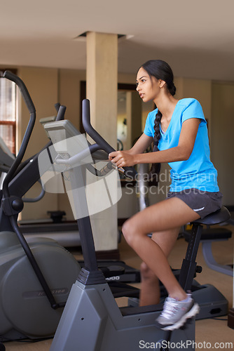 Image of Woman, cardio and exercise bike in gym, active and stationary machine for workout at club. Female person, body health and cycling for strength training, challenge and equipment for fitness or action