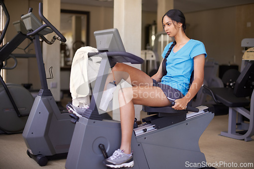 Image of Woman, fitness and exercise bike in gym, wellness and stationary machine for workout at club. Female person, cardio and cycling for strength training, athlete and equipment for challenge and health