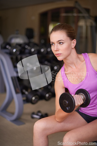 Image of Dumbbell, fitness and woman in a gym, workout and strength training with wellness and exercise with equipment. Thinking, serious face or girl in a health center and progress with weights or challenge