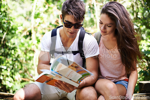 Image of Couple, map and backpack for hiking in forest with reading for thinking, holiday or search by trees. Man, woman and bag for trekking, direction or journey in jungle with book for vacation in Colombia