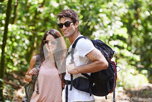 Image of Happy couple, backpack and hiking with sunglasses in nature for adventure or outdoor journey together. Young man, woman or hiker with smile, bag and bonding for trekking or walk in forest or woods