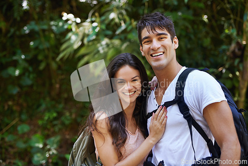 Image of Happy couple, portrait and hiking with backpack in nature for adventure or outdoor journey together. Face of young man, woman or hiker with smile, hug and bag for bonding, trekking or walk in forest