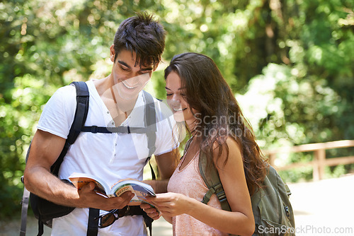 Image of Couple, map and reading for hiking in woods with smile for thinking, holiday and ideas on path. Man, woman and bag for trekking, direction and search in rainforest with book for location in Colombia