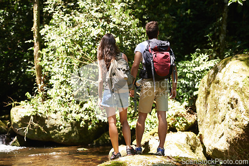 Image of Couple, back and rocks for hiking by river, environment and memory on holiday with holding hands. Man, woman and bag for trekking, direction or search in rainforest with water at location in Colombia