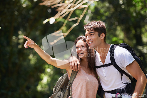 Image of Couple, point and smile for hiking in jungle with sign for thinking, holiday and happy on path. Man, woman and bag for trekking, direction and search in rainforest with ideas at location in Colombia