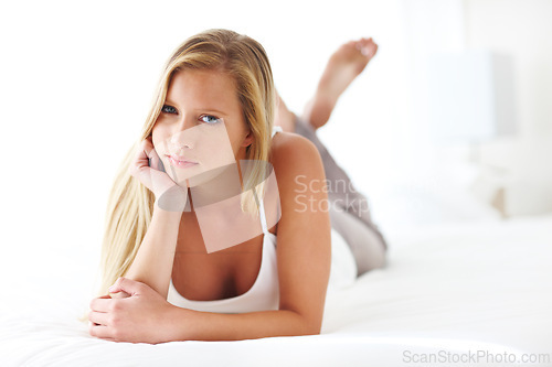 Image of Portrait, relax and morning with woman in bedroom of home on weekend for comfortable time off. Face, peace and quiet with serious young person lying on bed in apartment for break, pause or rest